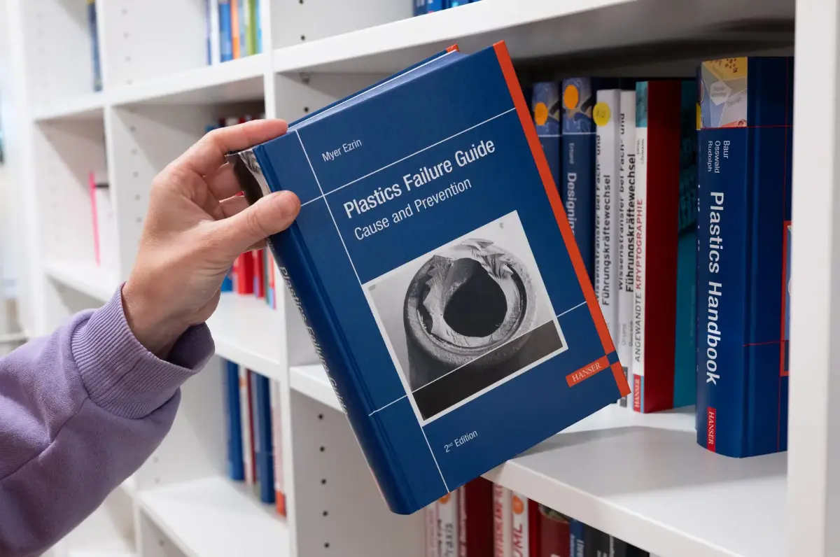 A hand taking out a textbook out of the book shelf