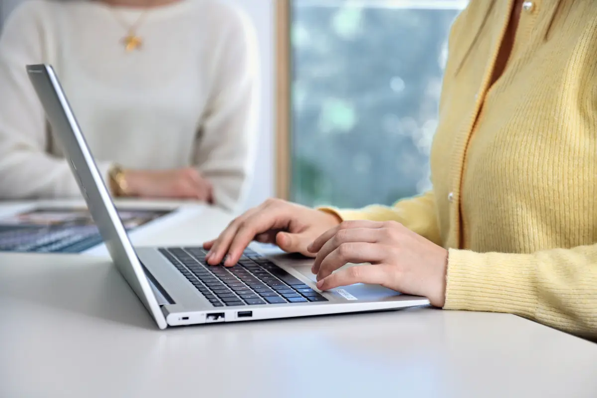 Hands typing into a laptop
